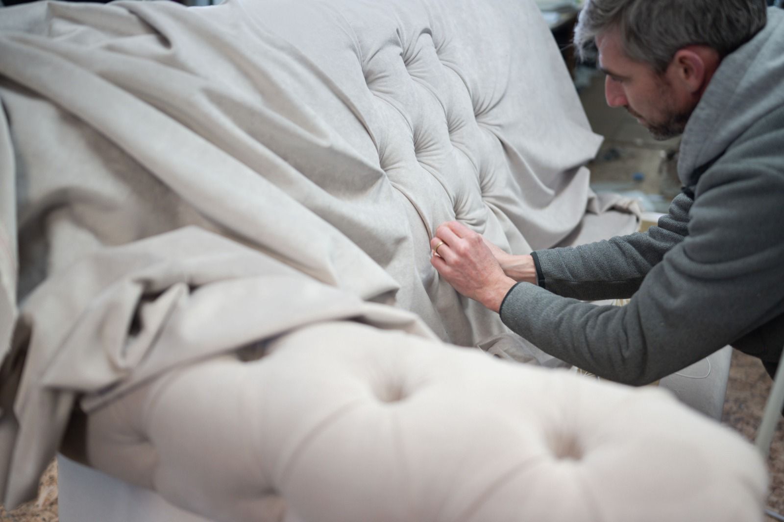 Craftsman stitching upholstery on a sofa frame in the McGuckin workshop
